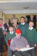 Pupils of St Patrick's School present a card and red hat to Father Harrington
